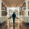 a person walking through a hallway with art on the walls